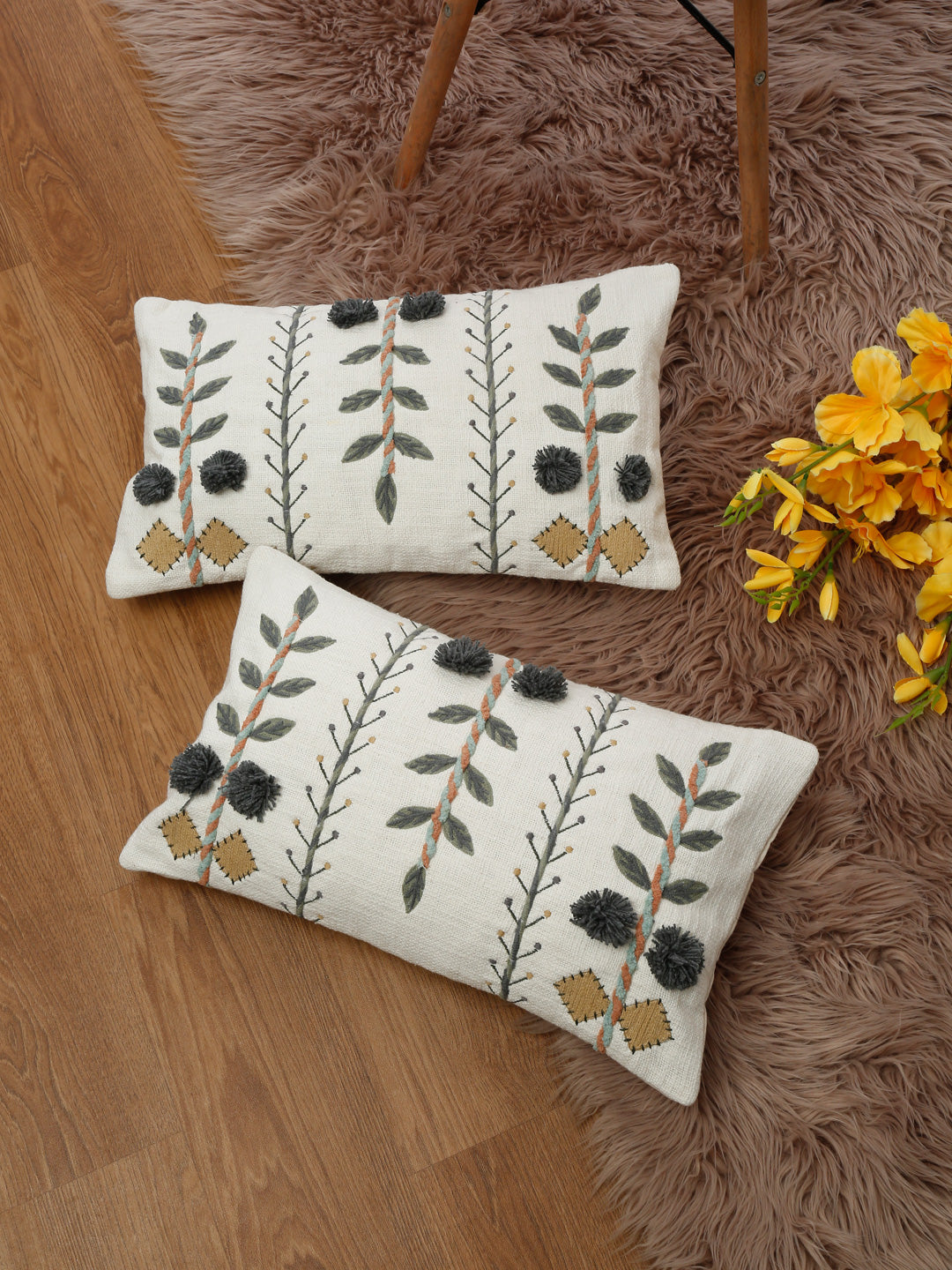 Hand embroidered cotton pillow covers styled on rug and wooden floor
